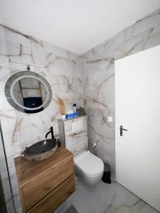 ein Badezimmer mit einem Waschbecken, einem WC und einem Spiegel in der Unterkunft Studio magnifique avec terrasse spacieuse Loèche-les-Bains Vacances in Leukerbad