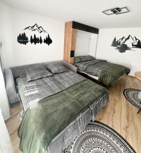 two beds in a bedroom with mountains on the wall at Studio magnifique avec terrasse spacieuse Loèche-les-Bains Vacances in Leukerbad