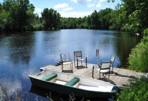 a boat and chairs on a dock on a lake at Chalet Du Marais in Saint-Paulin