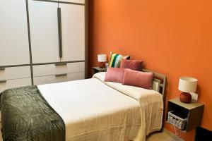um quarto com uma parede laranja e uma cama com almofadas em Resto appartamento 5 em Turim