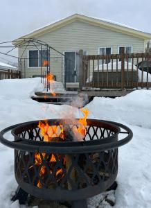 a fire pit in the snow in front of a house at Chalet Du Marais in Saint-Paulin