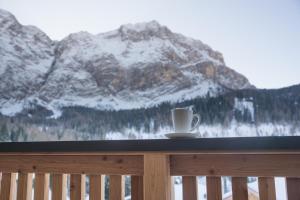 a coffee cup on a balcony with a mountain view at Ciasa Plandros Apartments in La Valle