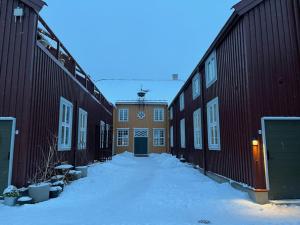 a snow covered alley between two buildings with a door at Ny og moderne leilighet, midt i byen1 in Trondheim