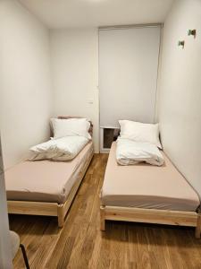 two beds in a room with wooden floors at Ny og moderne leilighet, midt i byen1 in Trondheim