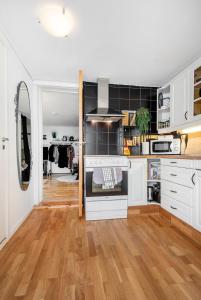 a kitchen with white cabinets and a hard wood floor at Apartment close to Aalesund center in Ålesund
