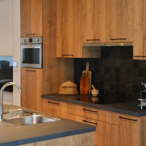 a kitchen with wooden cabinets and a sink at Gezellig appartement Liva in Blankenberge