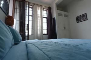 een slaapkamer met een blauw bed en 2 ramen bij CHILCHILL Elite Residences BKK2 in Phnom Penh