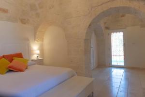 um quarto com uma cama branca e uma janela em Masseria Carperi in the heart of Valle d'Itria em Cisternino