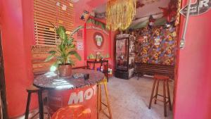 Habitación con paredes rosas, mesa y piano en Red Monkey Hostel Barra Funda en São Paulo