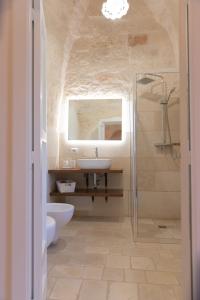 uma casa de banho com um lavatório, um WC e um espelho. em Masseria Carperi in the heart of Valle d'Itria em Cisternino
