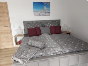1 dormitorio con cama con colcha y almohadas grises en Premium Vulkaneifel Chalet, en Lutzerath