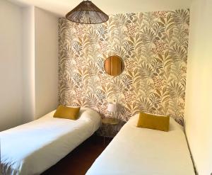 two twin beds in a room with a wallpaper at Jardín privado # Netflix # 500m de la playa in Vera