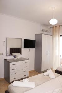 um quarto com 2 camas e uma cómoda e uma televisão em ElMar Apartments em Saranda