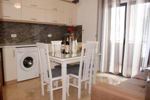 uma cozinha com uma mesa com cadeiras e uma máquina de lavar roupa em ElMar Apartments em Saranda