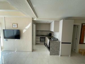 a kitchen with white cabinets and a flat screen tv at Apartment Monserrate K atico in Torrevieja +3 photos