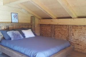 a bed in a cabin with a wooden ceiling at Le Chalet de Bequi in Bellefontaine