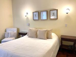 um quarto com uma cama branca e duas fotografias na parede em Hotel Villa Inés Mendoza em Mendoza