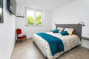 een slaapkamer met een bed en een rode stoel bij Le cœur de l'eau in Vittel