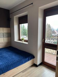 a bedroom with a blue bed and a window at Błękitne Wierchy in Murzasichle +4 photos
