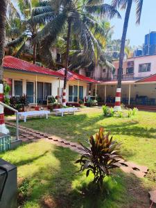 a courtyard with palm trees and a building at The Sunbliss Cottages in Morjim
