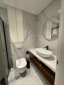 a white bathroom with a toilet and a sink at Uzelac apartment with pool in Makarska
