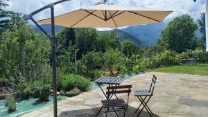 a table and chairs under an umbrella on a patio at Casa Vacanza L'infinito per escursionisti - gruppi e famiglie in Pessinetto