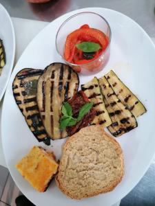 a plate of food with grilled meat and a bowl of tomatoes at Hotel Villa Giovanna in Torre Suda +87 photos
