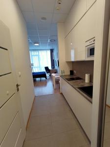 a kitchen with white cabinets and a living room at Zlatarooms 217 in Warsaw