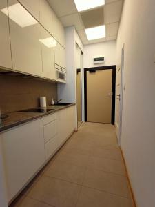 a kitchen with white cabinets and a hallway at Zlatarooms 217 in Warsaw