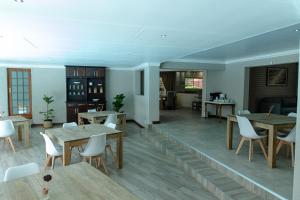 a dining room with wooden tables and white chairs at Tristan's Place Guest House in Klerksdorp