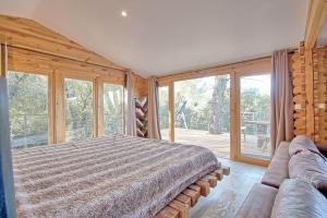 - une chambre avec un lit et une grande fenêtre dans l'établissement romantique cabane perchée avec spa vue panoramique Le Mas des Faraches, à Solliès-Toucas
