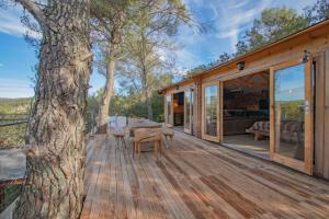 une terrasse en bois avec une table et un arbre dans l'établissement romantique cabane perchée avec spa vue panoramique Le Mas des Faraches, à Solliès-Toucas