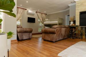 a living room with two couches and a television at Tristan's Place Guest House in Klerksdorp