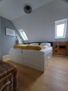 um quarto com uma cama branca com lençóis amarelos em Moewennest-by-DeJu-Norderney em Norderney