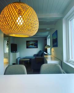 uma sala de estar com um lustre e um sofá e cadeiras em Kirkjatún em Miðvágur