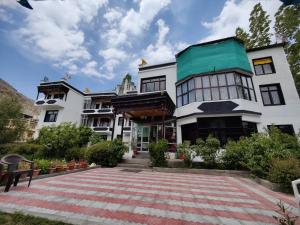 Dream Ladakh Guest House في ليه: مبنى ابيض كبير بسقف اخضر