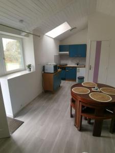 een kamer met een tafel en een keuken met blauwe kasten bij Studio Sulniac Golfe du morbihan in Sulniac