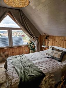 a bed in a room with a large window at REST HOUSE WDZYDZE DOMKI NAD JEZIOREM in Wdzydze Kiszewskie