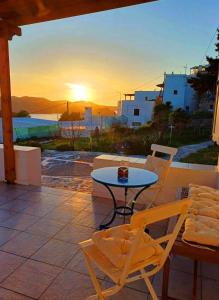 a table and chairs on a patio with the sunset at Georgia Rooms Milos in Plaka Milou