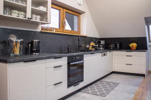 a kitchen with white cabinets and black counter tops at Apartament Sarenka in Rogożnik
