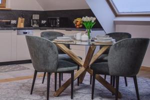 a dining room table with four chairs and a kitchen at Apartament Sarenka in Rogożnik