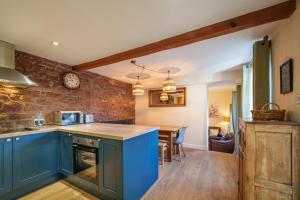 een keuken met blauwe kasten en een eetkamer bij 2 Eden Grove Cottages in Armathwaite