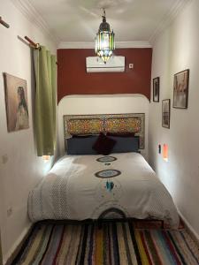 um quarto com uma cama e um lustre em Riad N10 em Marraquexe