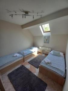 a attic bedroom with two beds and a window at Lujza Apartman Gödöllő in Gödöllő