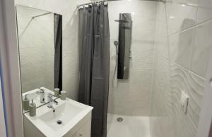 een witte badkamer met douche en wastafel bij Studio agréable in Le Havre