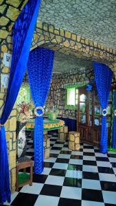 a room with blue curtains and a checkered floor at Châteaux Yolande in Mahajanga