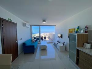 sala de estar con sofá azul y ventana en Sunshine Apartments Mellieha - modern two bedroom penthouse with terrace, en Mellieħa