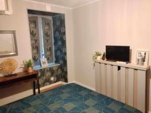 a living room with a tv and a desk with a computer at Chambre d'hote Familiale de la maison Bleue in Lanvallay