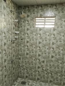 a bathroom with a shower with a stone wall at Milk House Cottage in Udawalawe