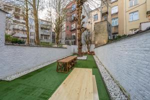 a wooden bench sitting on a green floor next to a building at Euro Edens Brussels - Family Home & Free Gym Access in Brussels